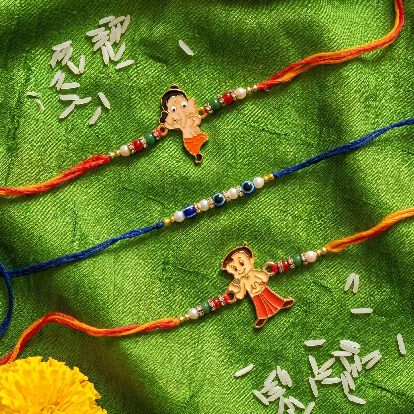 Ribbon Candy – Set of 3 Rakhis-Chota Bheem Charm, Ganesha Charm, and Evil Eye Beads – Blue, Orange & Yellow