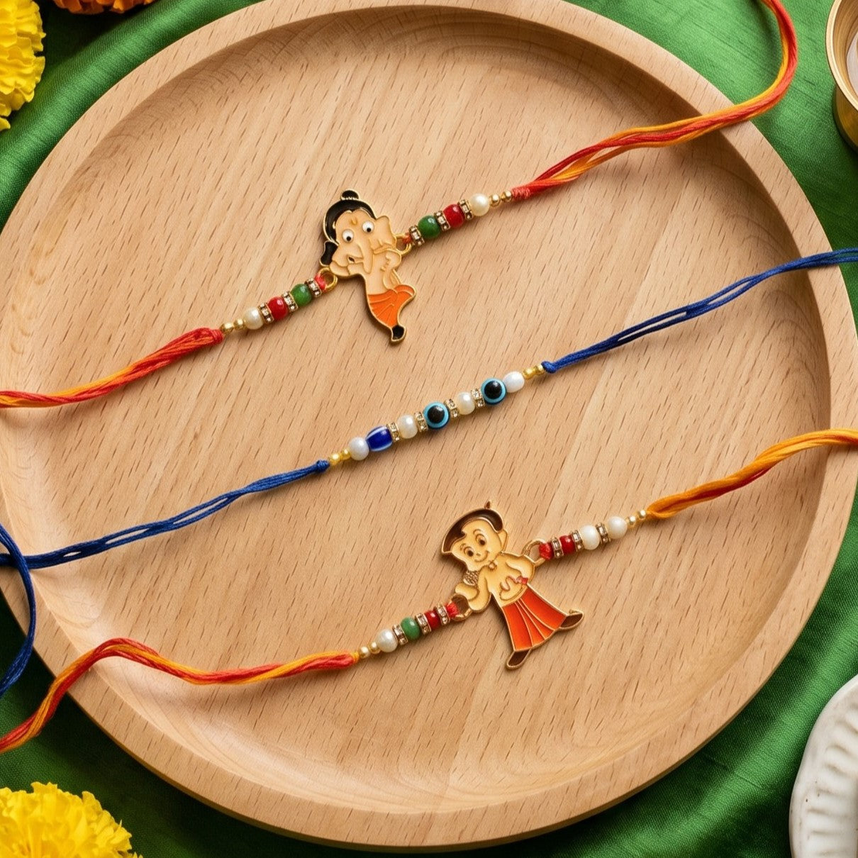 Ribbon Candy – Set of 3 Rakhis-Chota Bheem Charm, Ganesha Charm, and Evil Eye Beads – Blue, Orange & Yellow